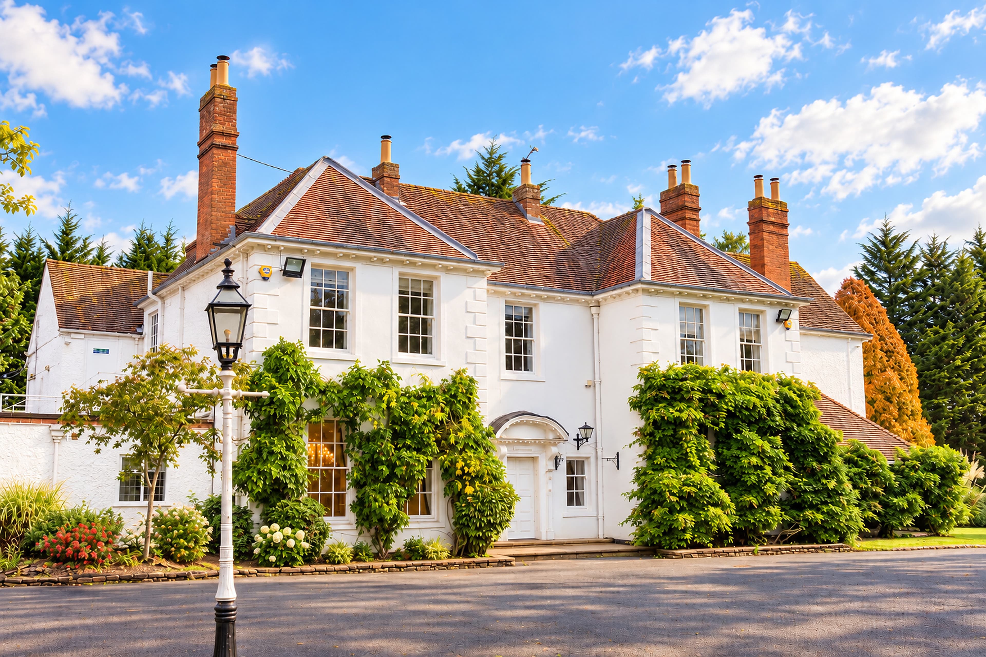 Longbridge Manor’s white façade, tiled roof and brick chimneys behind a traditional lantern on a white post